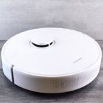 Een robotstofzuiger met dweilfunctie die soepel over een schone vloer beweegt in een moderne woonkamer.
